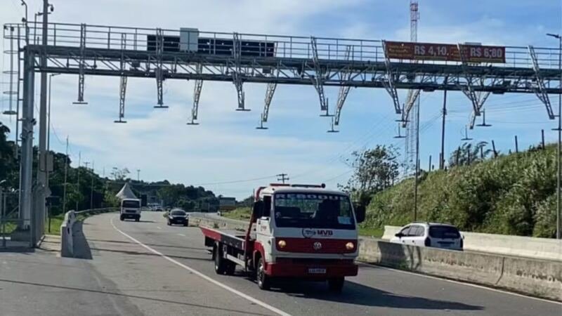 Pórtico de pedágio eletrônico sobre uma rodovia com veículos em circulação.