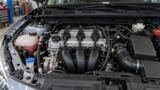 Foto de motor de três cilindros em cofre de carro sem identificação de marca.