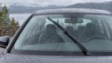 Para-brisa com gotas de chuva e limpador em movimento