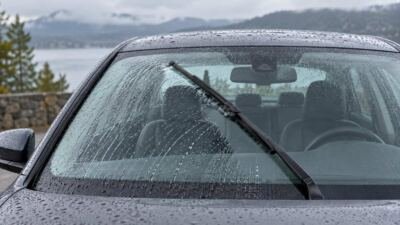 Para-brisa com gotas de chuva e limpador em movimento