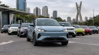 Carros elétricos alinhados diante de uma estação de recarga, com um BYD em primeiro plano.